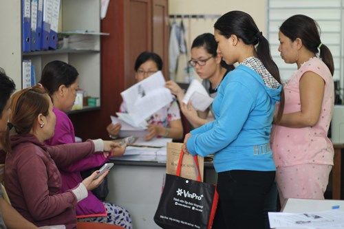 Tại trường Tiểu học Trần Văn Ơn, rất đông phụ huynh ngồi chờ đến lượt làm thủ tục nhập học trực tiếp cho con. 