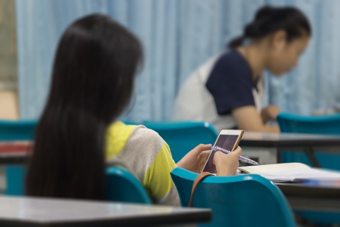 Một học sinh nữ đang dùng điện thoại di động. Ảnh: Shutterstock.